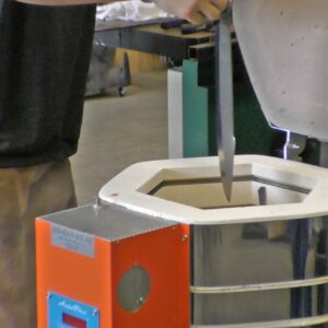 Man inserting a blade into a Jen-Ken Knife Kilns Vertical Air Bath 30 furnace