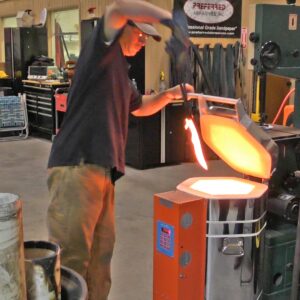 Man pulling a glowing hot blade from a Jen-Ken Knife Kilns Vertical Air Bath 30 furnace