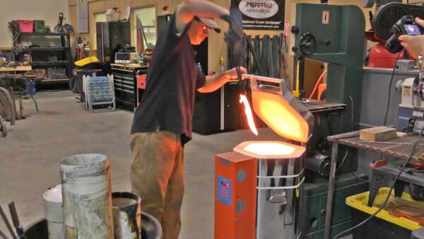 Man pulling a glowing hot blade from a Jen-Ken Knife Kilns Vertical Air Bath 30 furnace